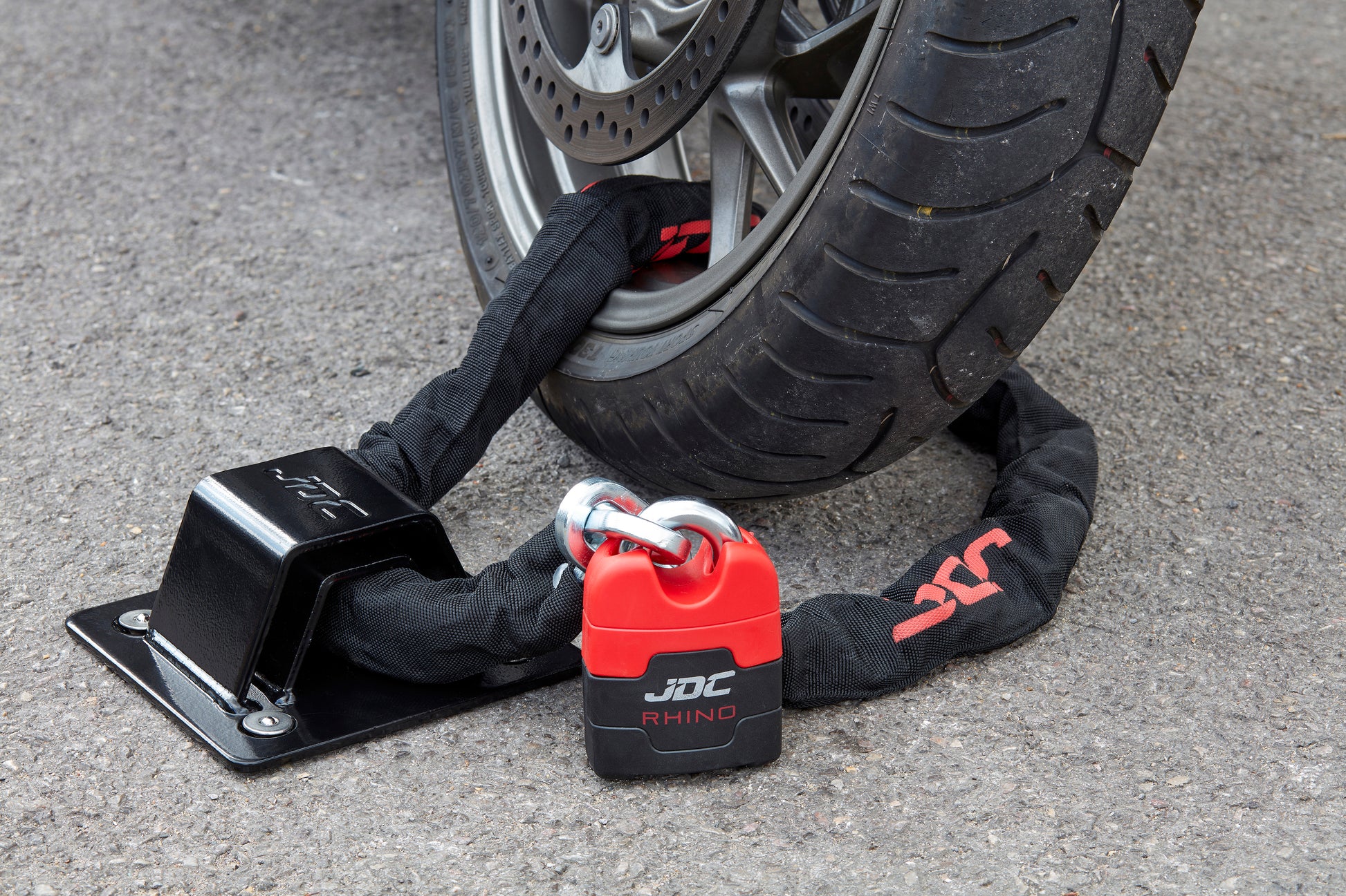 JDC Product's Sphere Ground Anchor Pro (black) shown with JDC Heavy Duty Bike Chain securing a motorbike